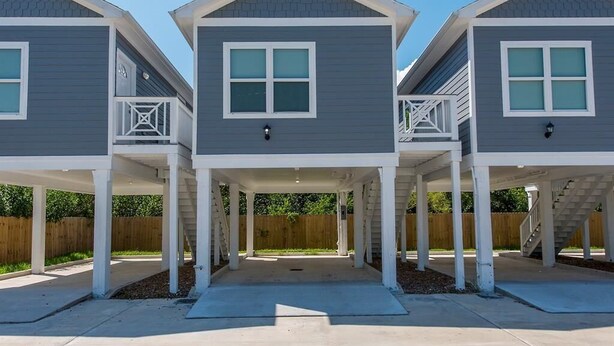 A row of three two-story houses with attached garages, white railings, and a central walkway. - Charming cabin with full kitchen! Unit 5/6 (San Leon)