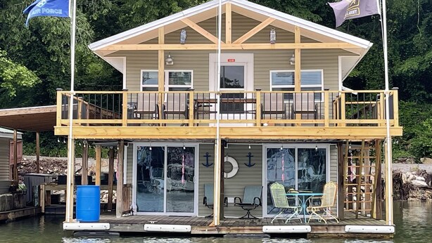 Une cabane avec un balcon, un quai et un drapeau.