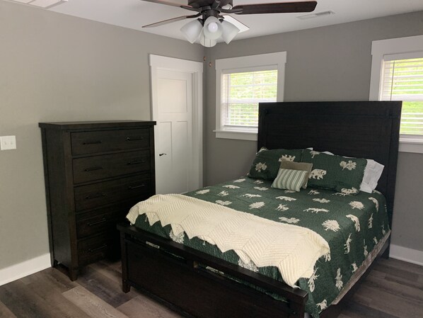 A bedroom with a dark wooden bed, a white door, and a window with blinds.