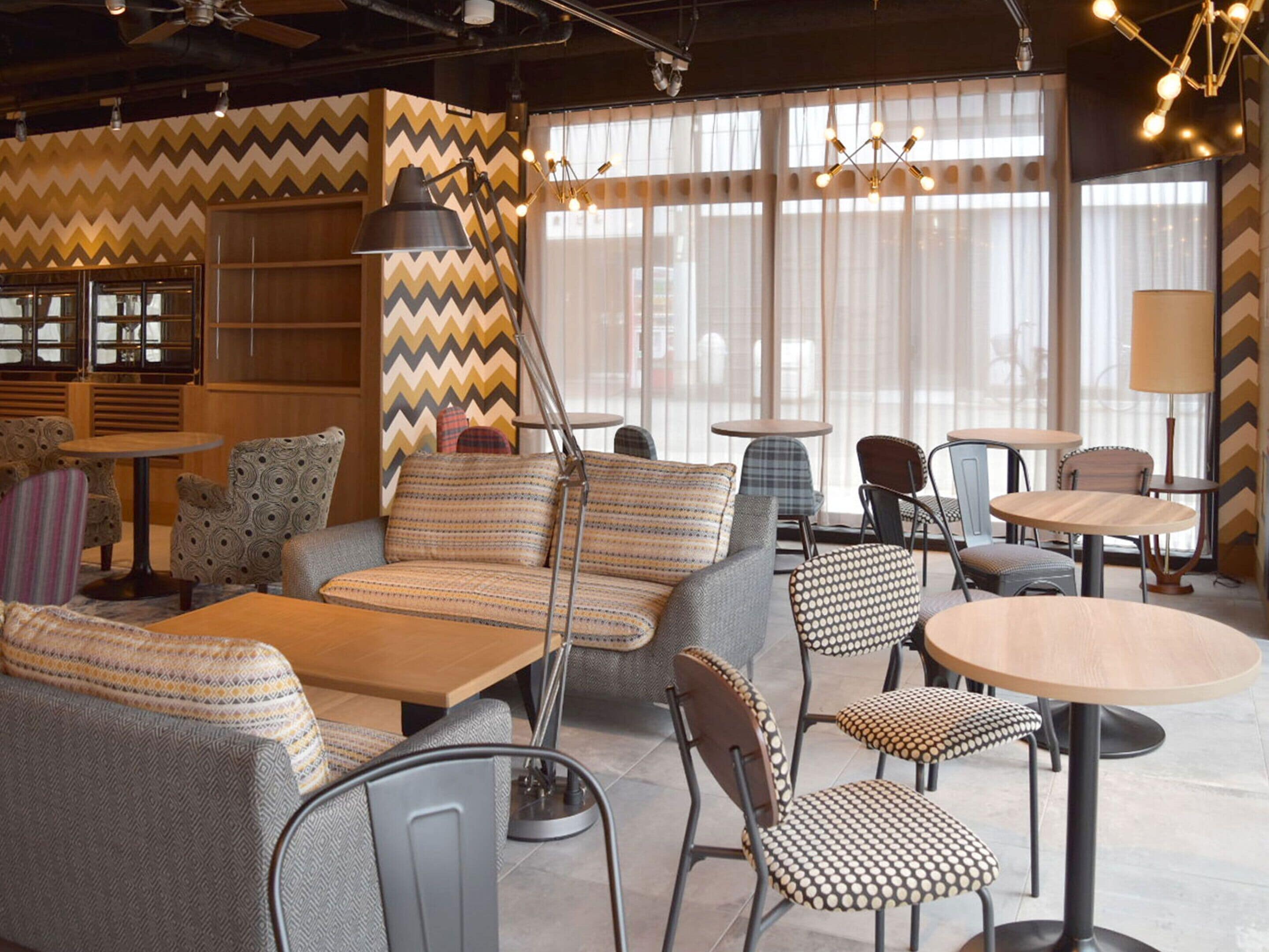 Un espace de détente moderne avec des canapés à motifs, des tables rondes et des chaises.