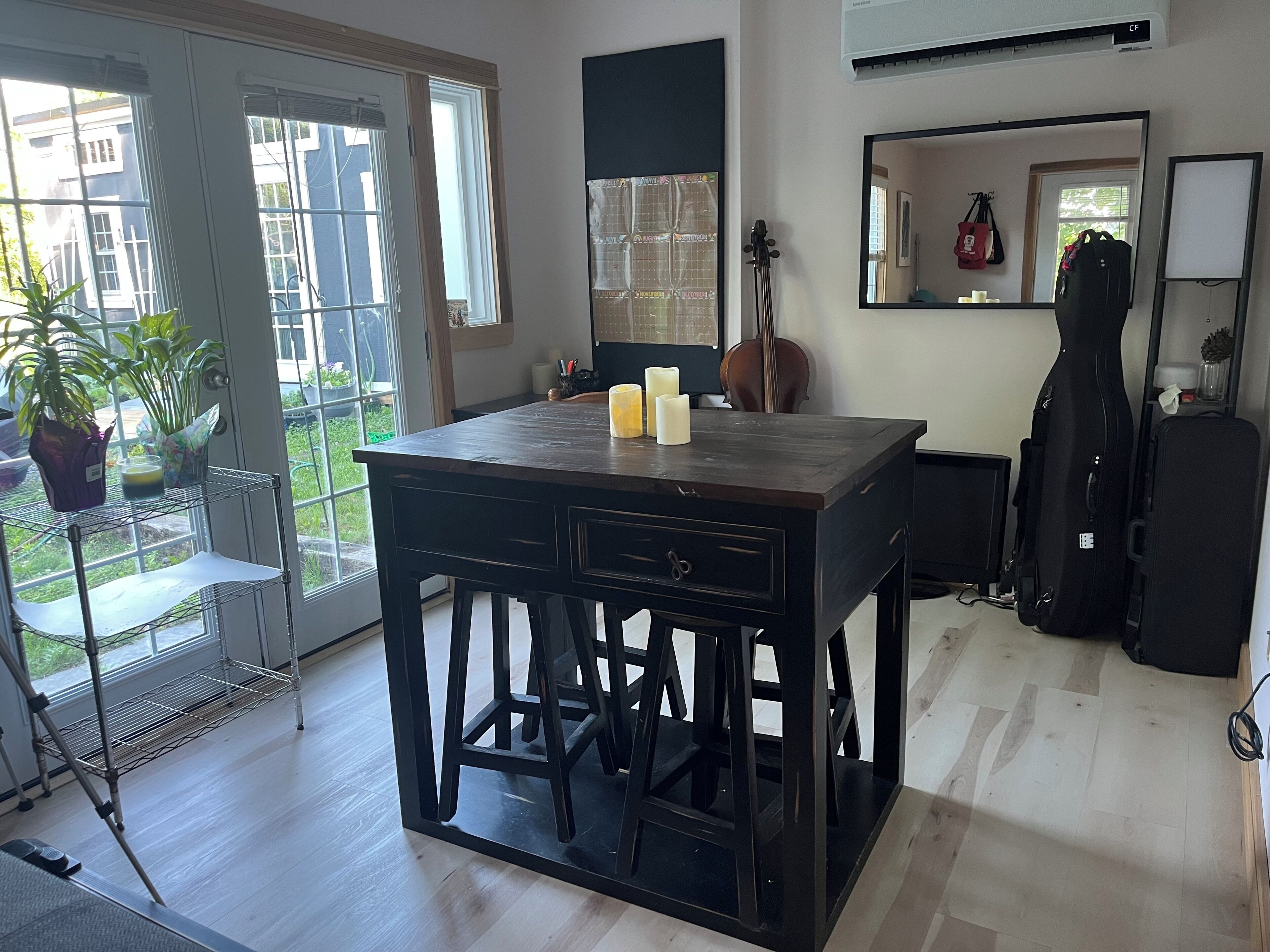 A room with a large window, a violin, a guitar, and a table with candles.