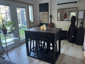 Une pièce avec une grande fenêtre, un violon, une guitare et une table ornée de bougies.