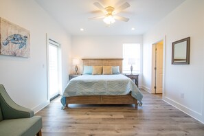 Relax in this serene bedroom with a large bed, wooden headboard, and comfortable armchair.