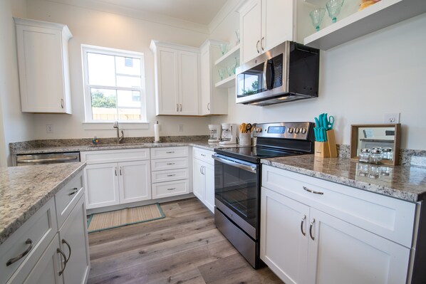 Equipped with a microwave, oven, and coffee maker, this kitchen offers a clean and minimalist design with ample natural light.