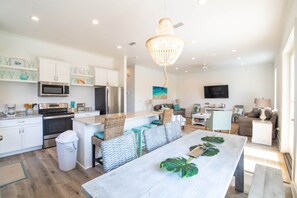 A modern kitchen with white cabinetry, a central island, and a dining area with a large table.