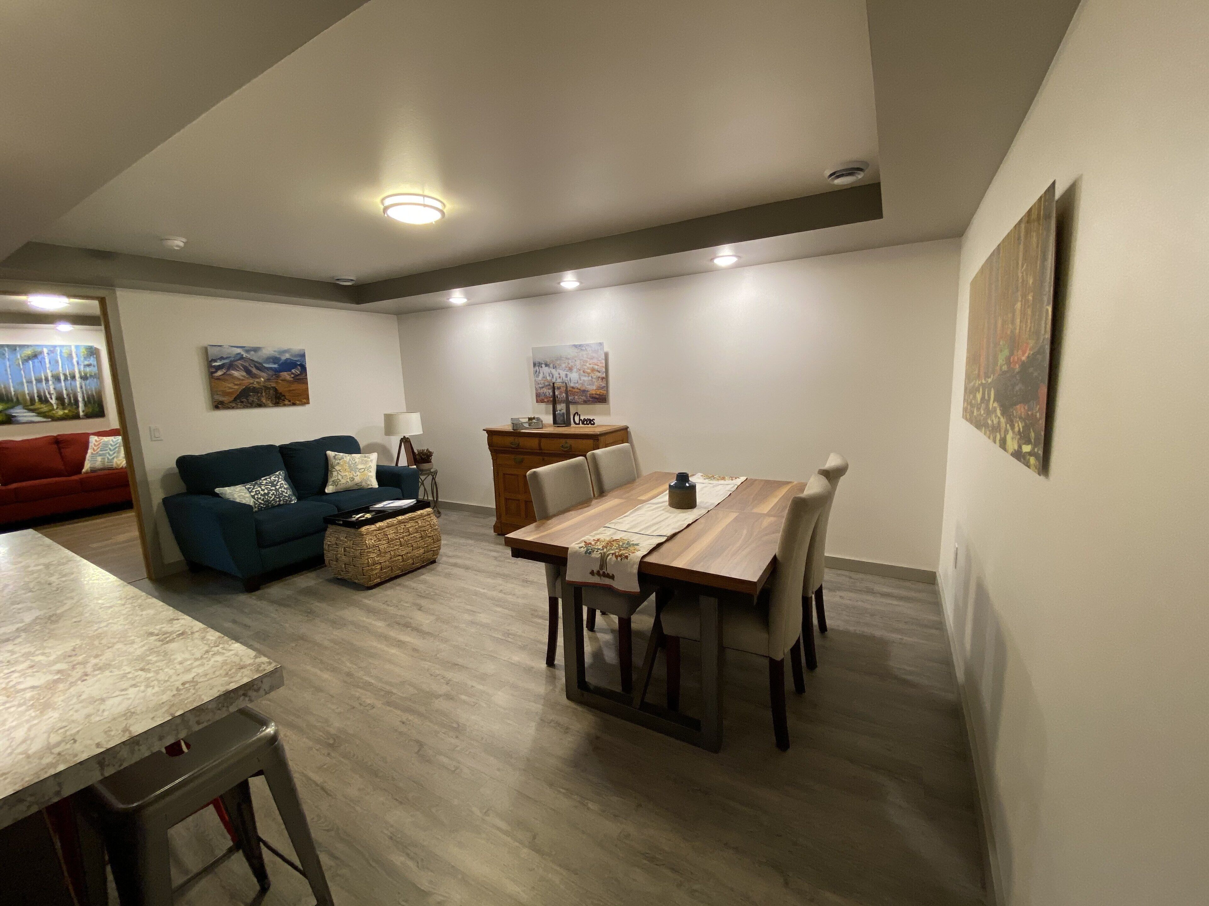 Un salon moderne avec un coin repas, comprenant une table à manger en bois, un canapé bleu et un divan rouge.