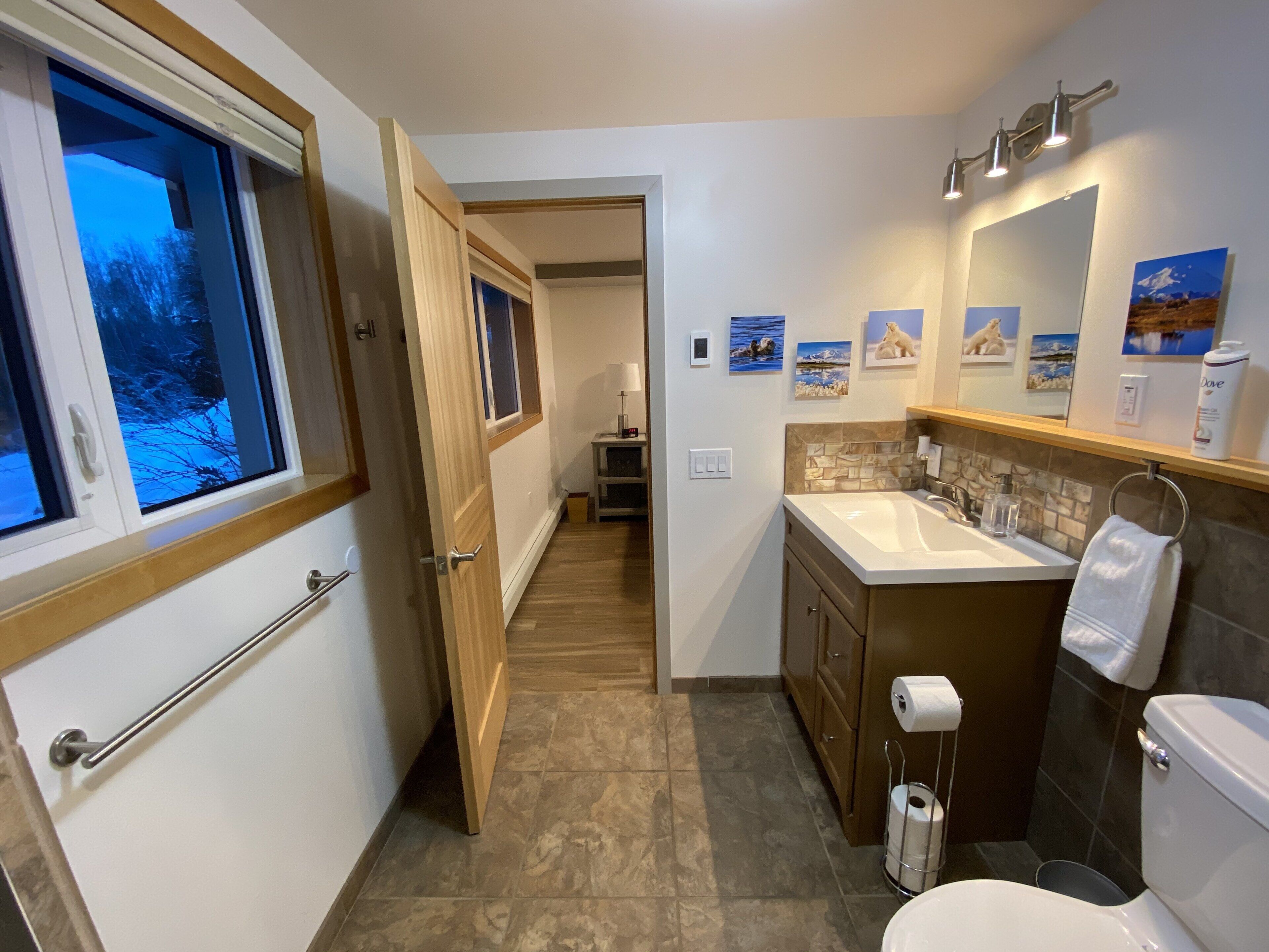 Un bagno moderno con una grande finestra, un lavandino, un water e una zona doccia.
