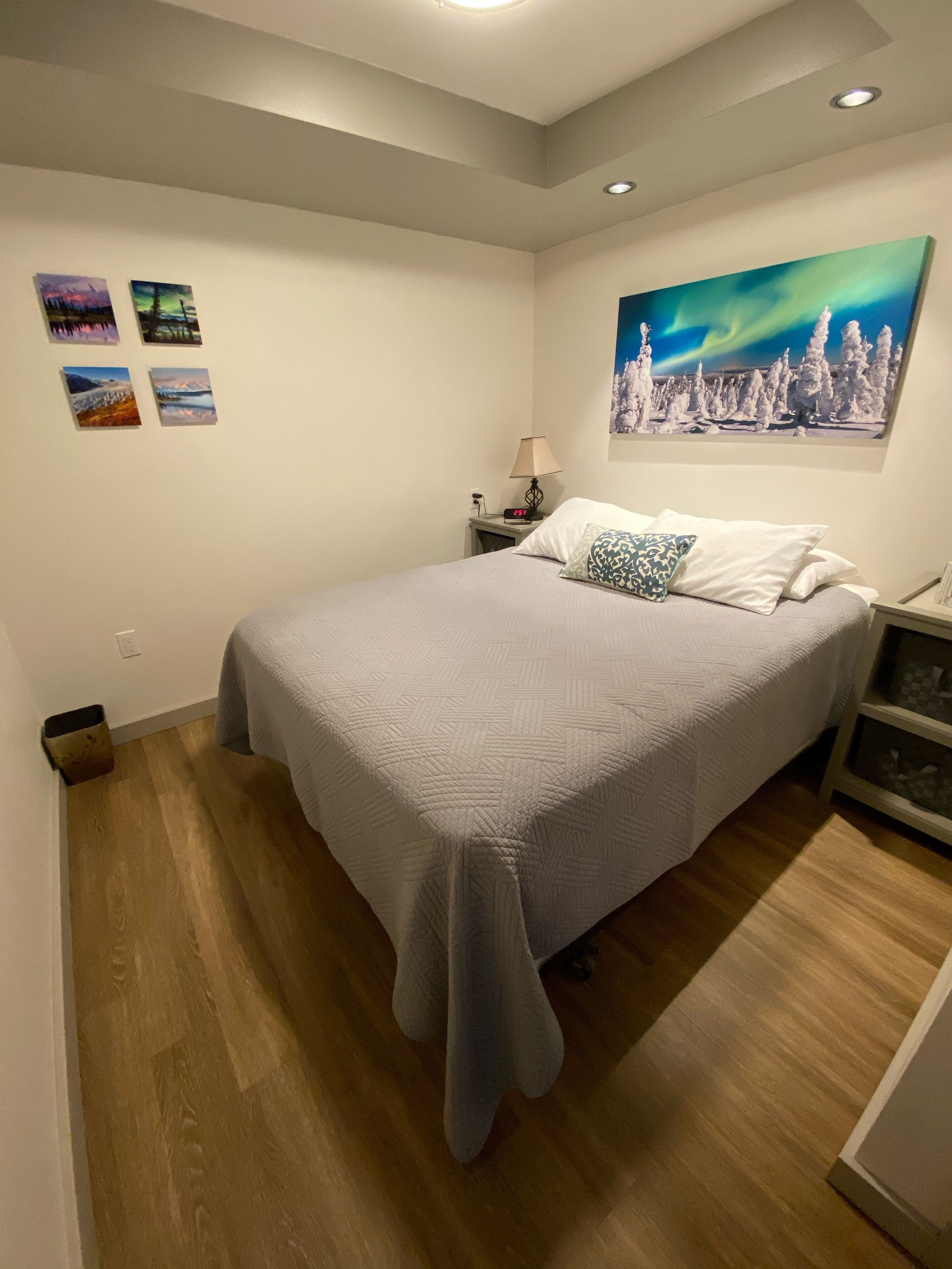 A bedroom with a bed, a nightstand, a lamp, and a painting on the wall.
