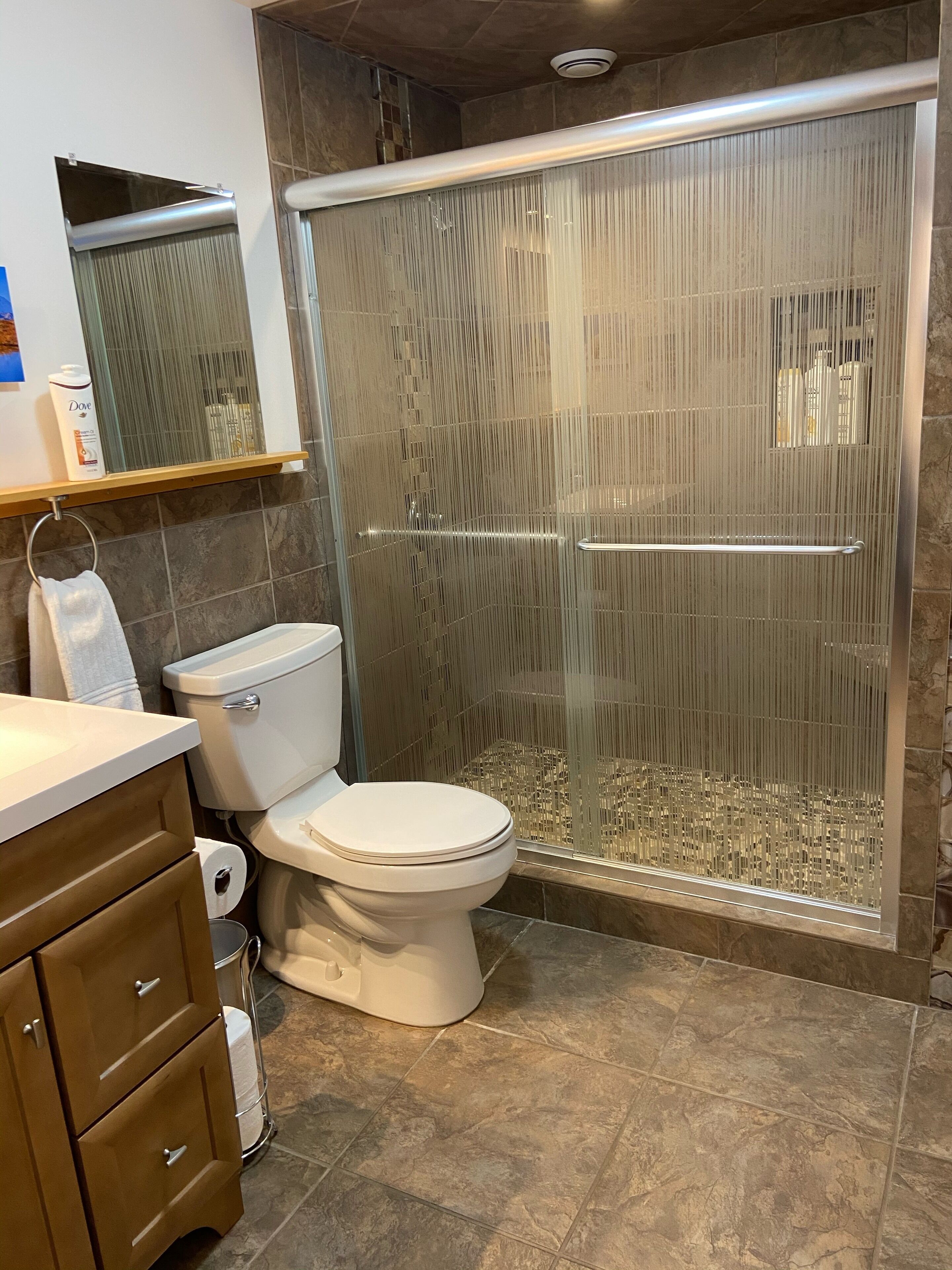Un baño con inodoro, cabina de ducha y tocador con cajones.