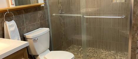 Un baño con inodoro, cabina de ducha y tocador con cajones.