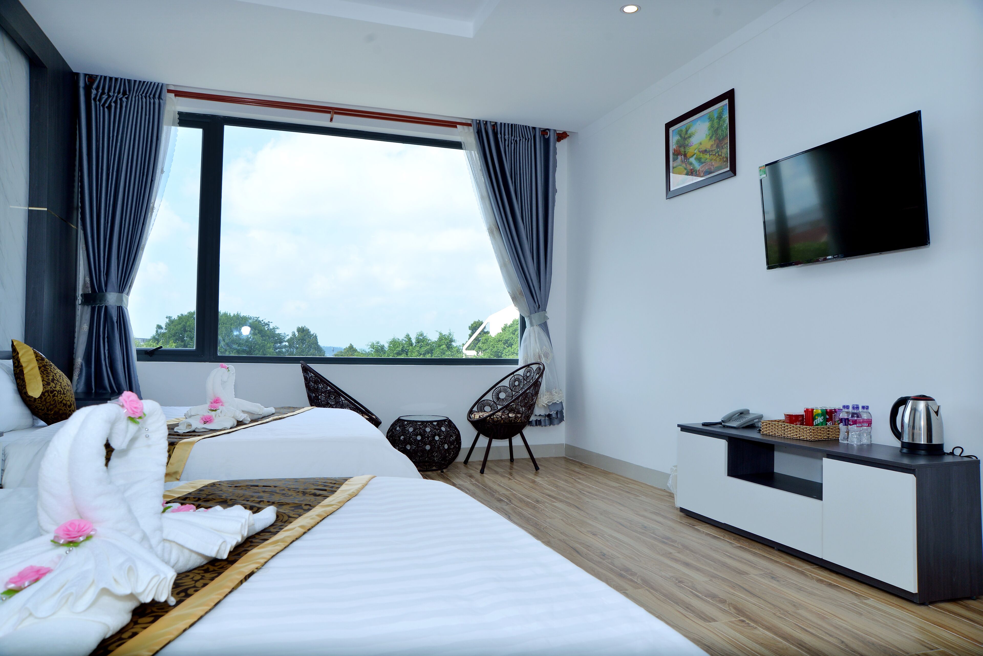 A modern hotel room with a large bed, a small desk, a chair, and a TV on the wall.