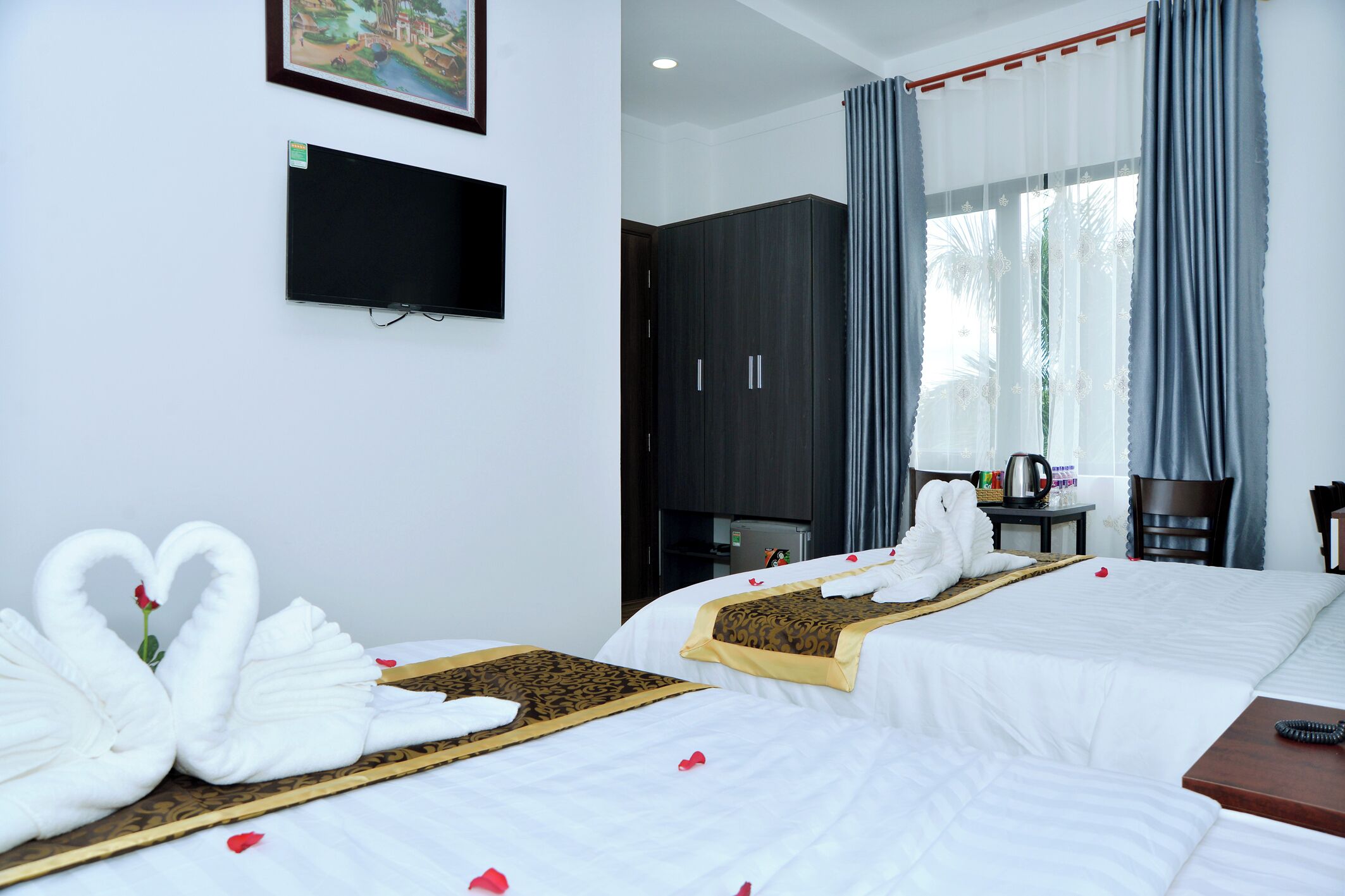 Habitación de hotel con cama, televisor de pantalla plana, armario y ventana con cortinas.