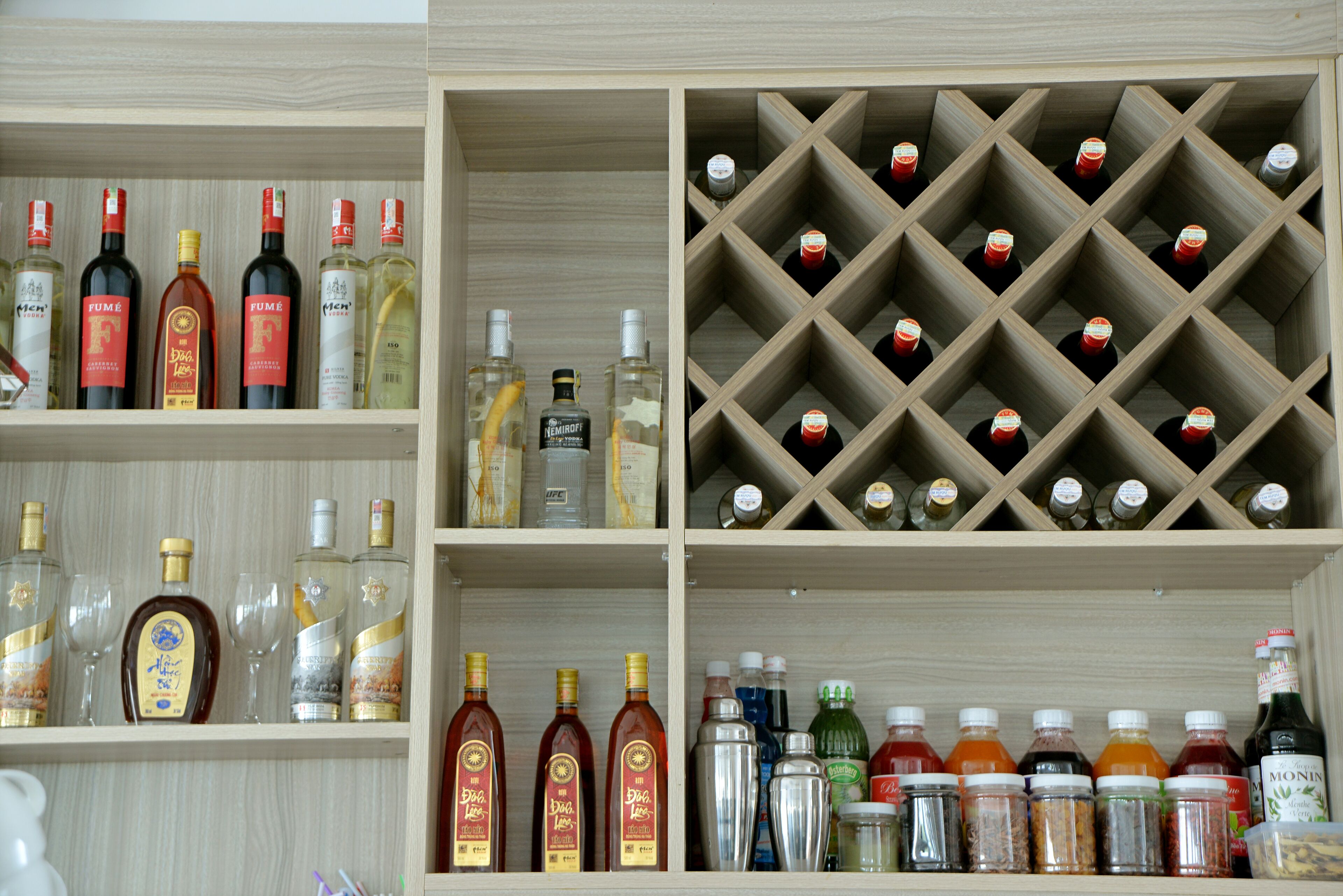 A wine rack with multiple bottles and a shelf with various liquor bottles.