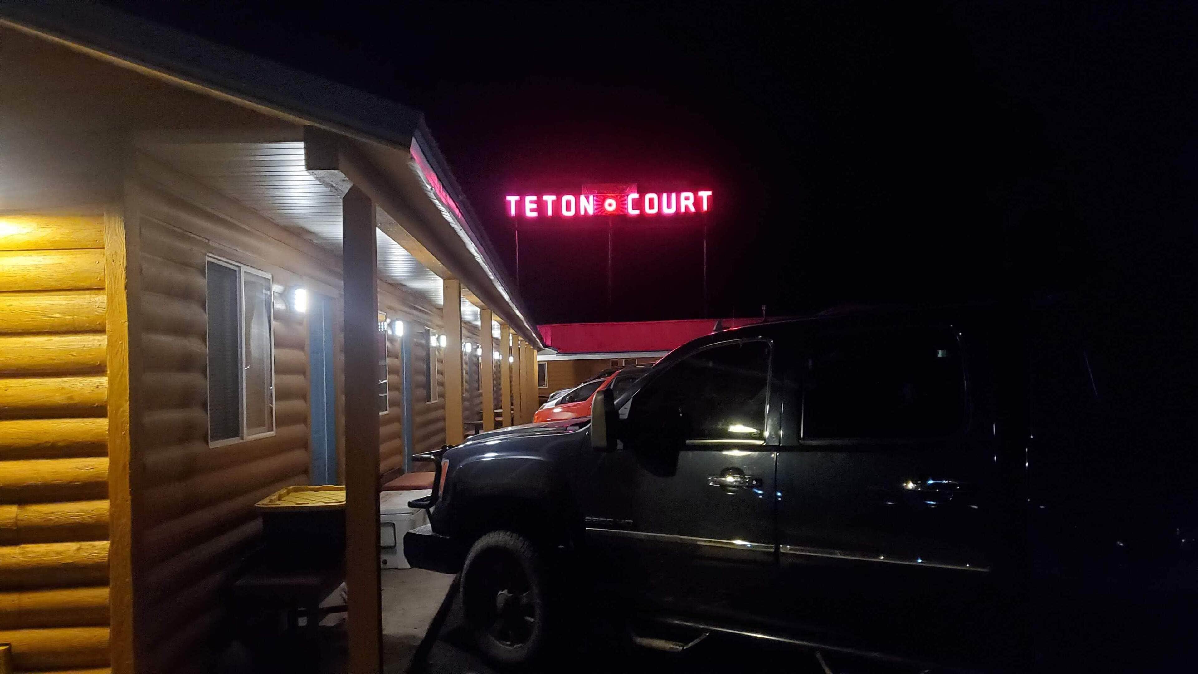A log cabin-style building with a neon sign reading "Teton Court."