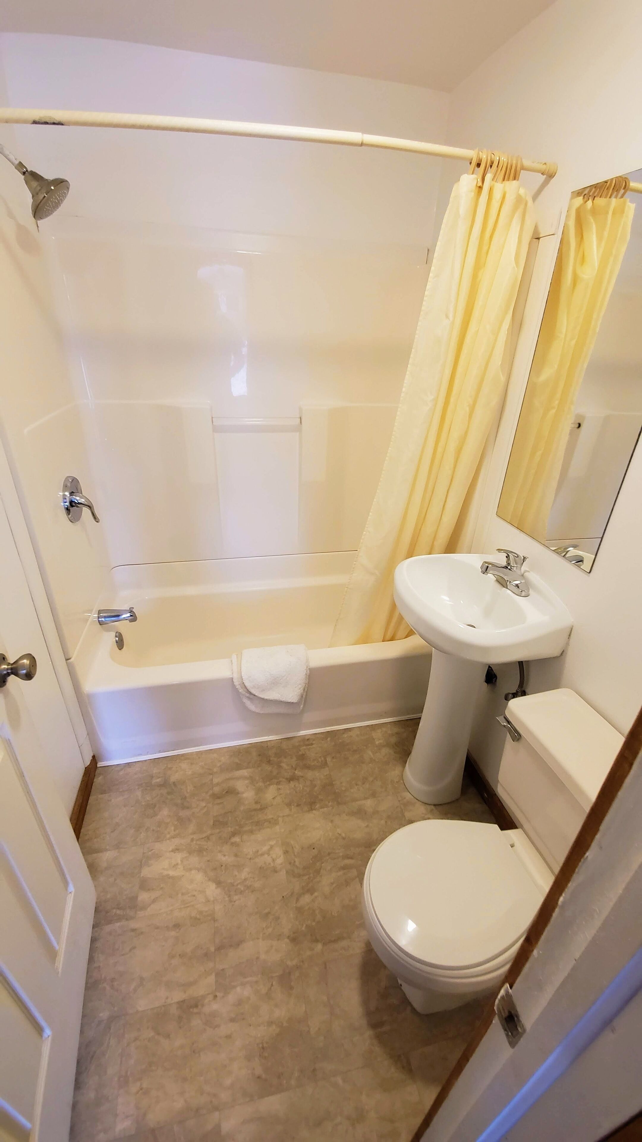Un baño pequeño y limpio con bañera, inodoro y lavabo.