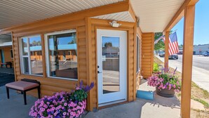 A wooden cabin with a porch, a table, and two flower planters. - Teton Court Motel (Pinedale)