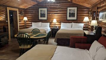 Una habitación tipo cabaña de troncos con dos camas, una mesa de comedor y sillas.