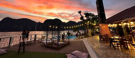Una terraza con piscina, asientos al aire libre y vistas al agua y las montañas.