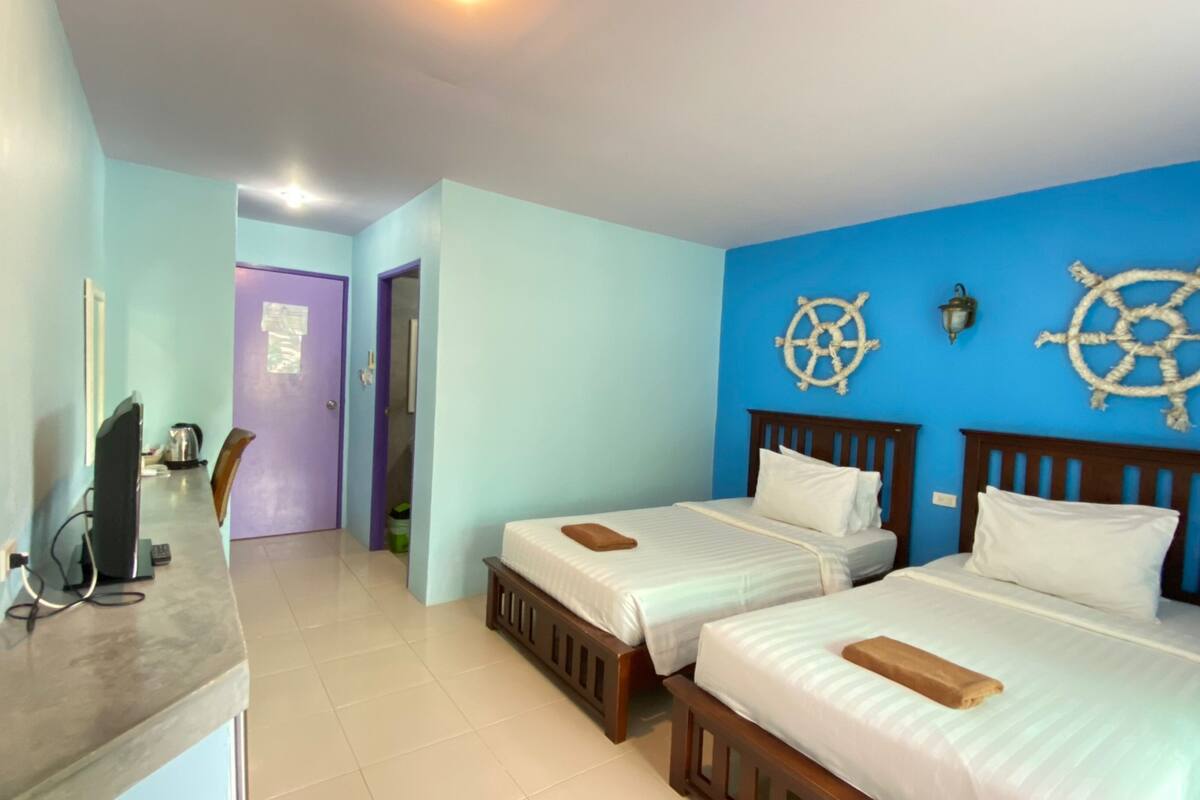 Une chambre d’hôtel avec deux lits, un bureau avec un ordinateur et une porte donnant sur une autre pièce.