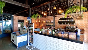 A bar area with a brick wall, shelves of beverages, and a counter with a beverage dispenser.