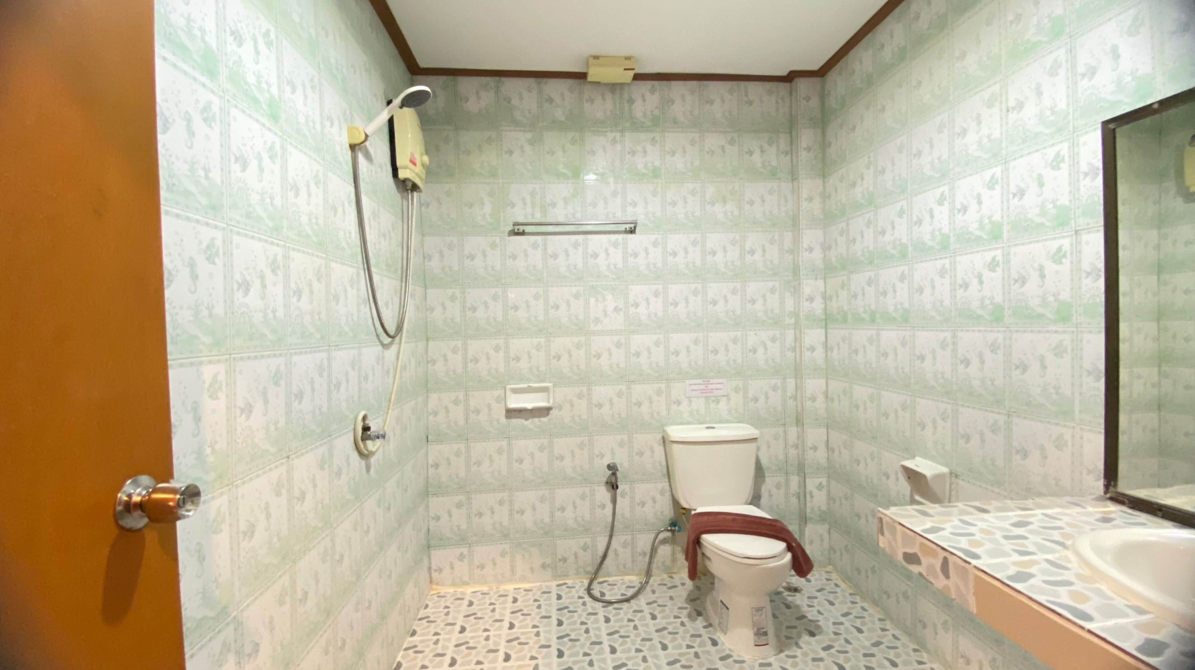 A bathroom with a toilet, a shower, and a sink.