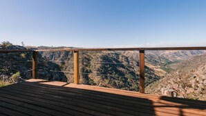 Un pontile in legno con ringhiera metallica che si affaccia su un paesaggio montuoso.