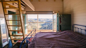 Una camera da letto con un letto, una scala, una finestra vista sulle montagne e un armadio.
