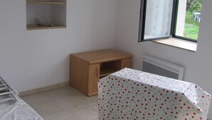 Ein Zimmer mit Fenster, einem kleinen Holztisch und einem Stuhl.