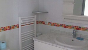 Ein Badezimmer mit Toilette, Waschbecken und Spiegel sowie einem Handtuchhalter.