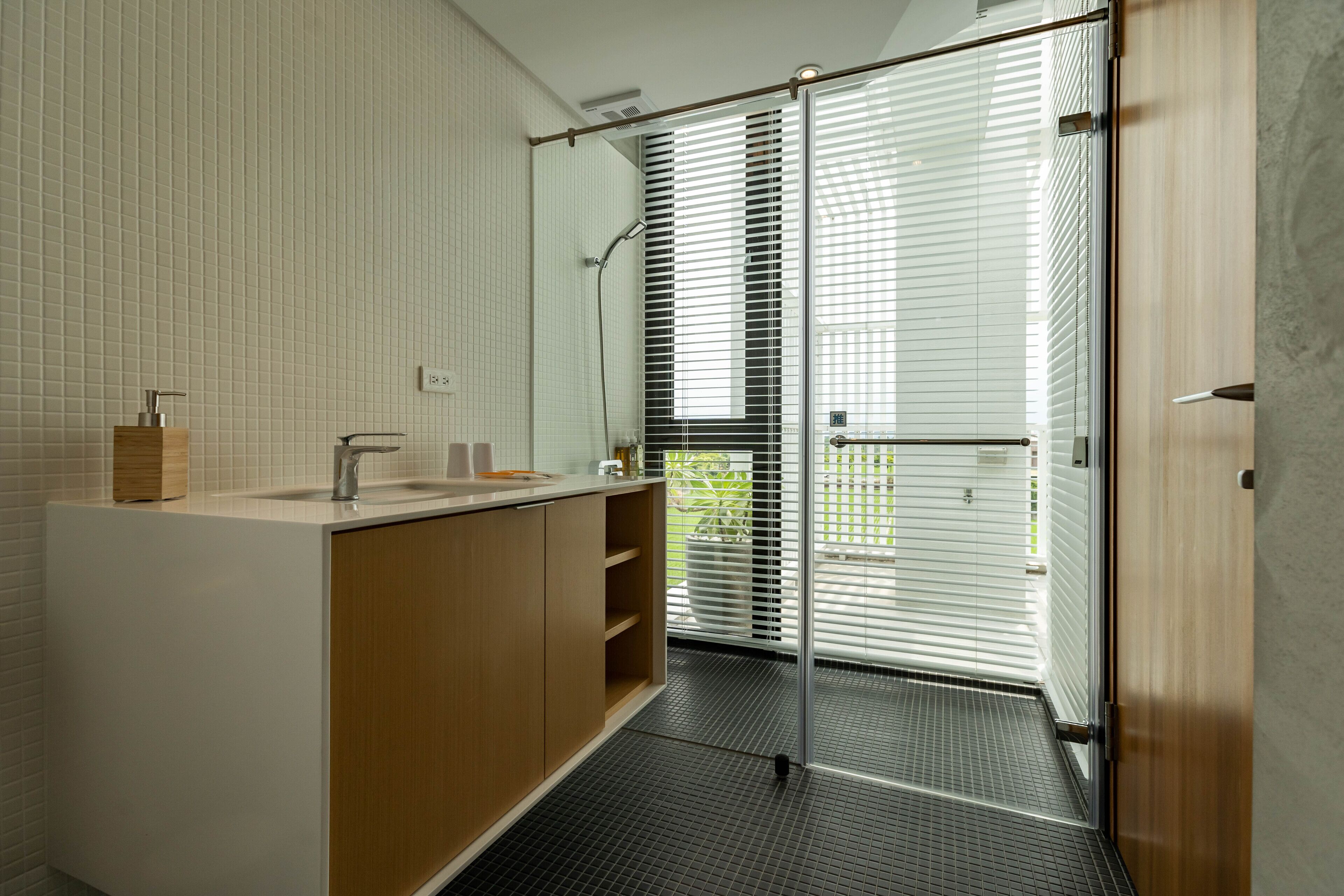 Ein modernes Badezimmer mit einem Holzlagerfläschchen, einer Duschkabine aus Glas und Blick ins Freie.