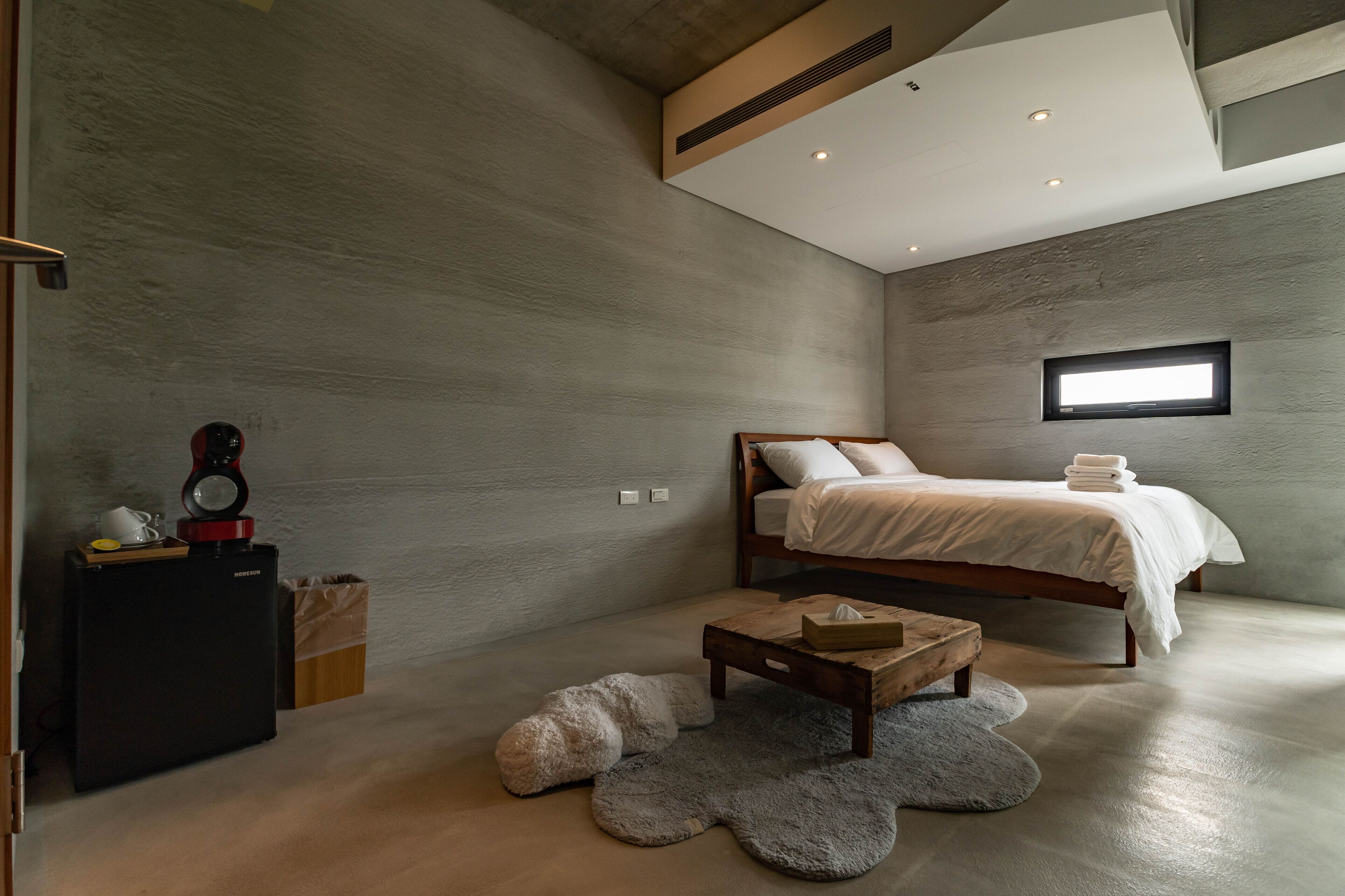 Un dormitorio moderno con cama, una mesita, un calentador y una ventana.