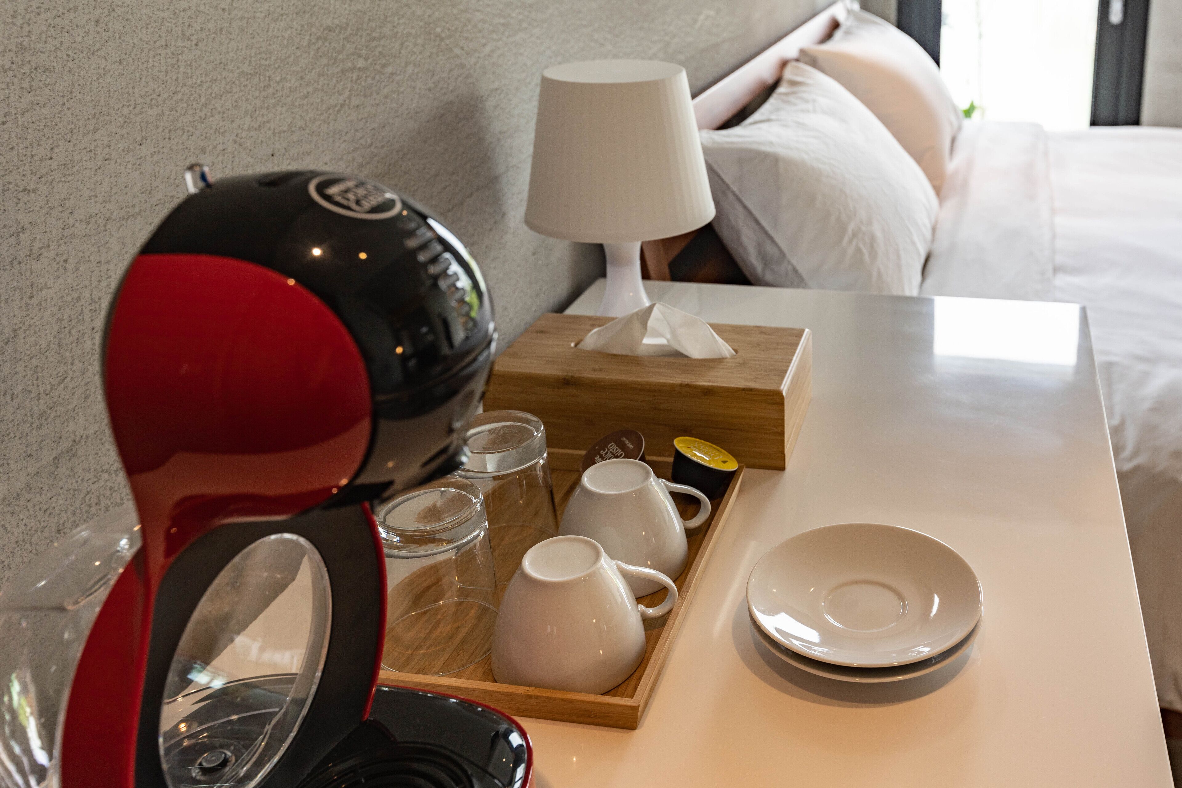 Een netjes opgemaakt ontbijtplateau met een koffiezetapparaat, kopjes, glazen en een bord op een tafel in een hotelkamer.