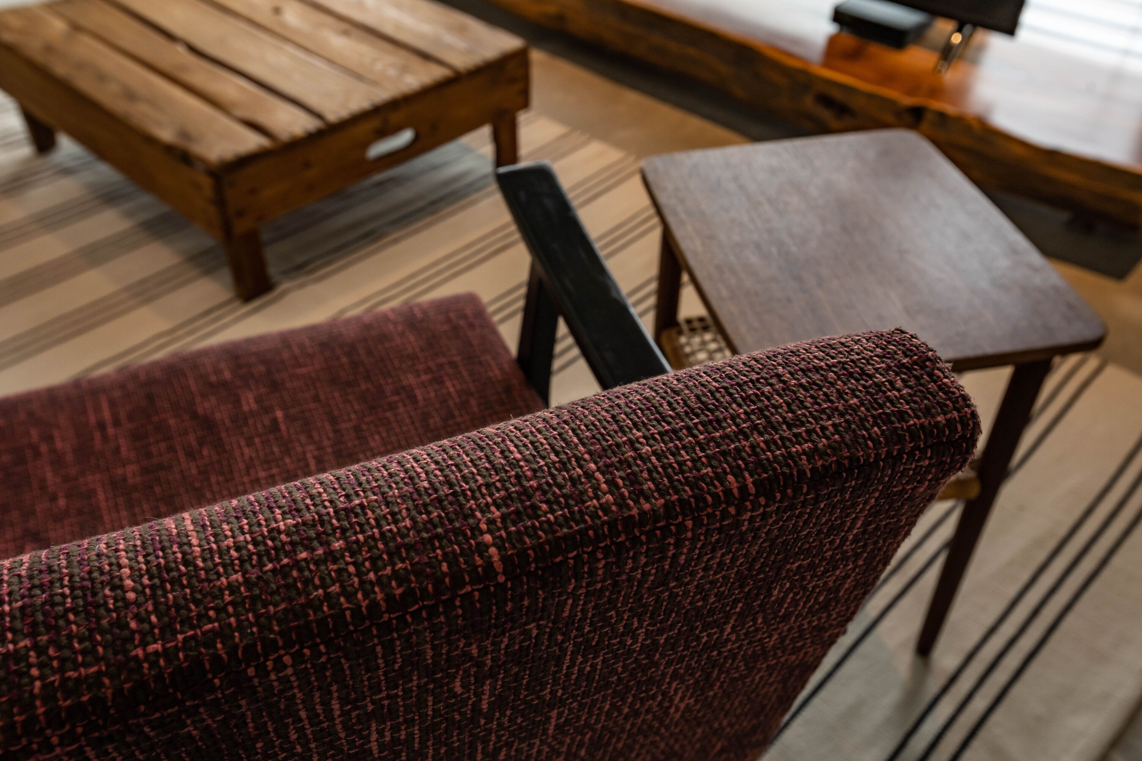 A room with a wooden coffee table, a small round table, and a woven armchair.