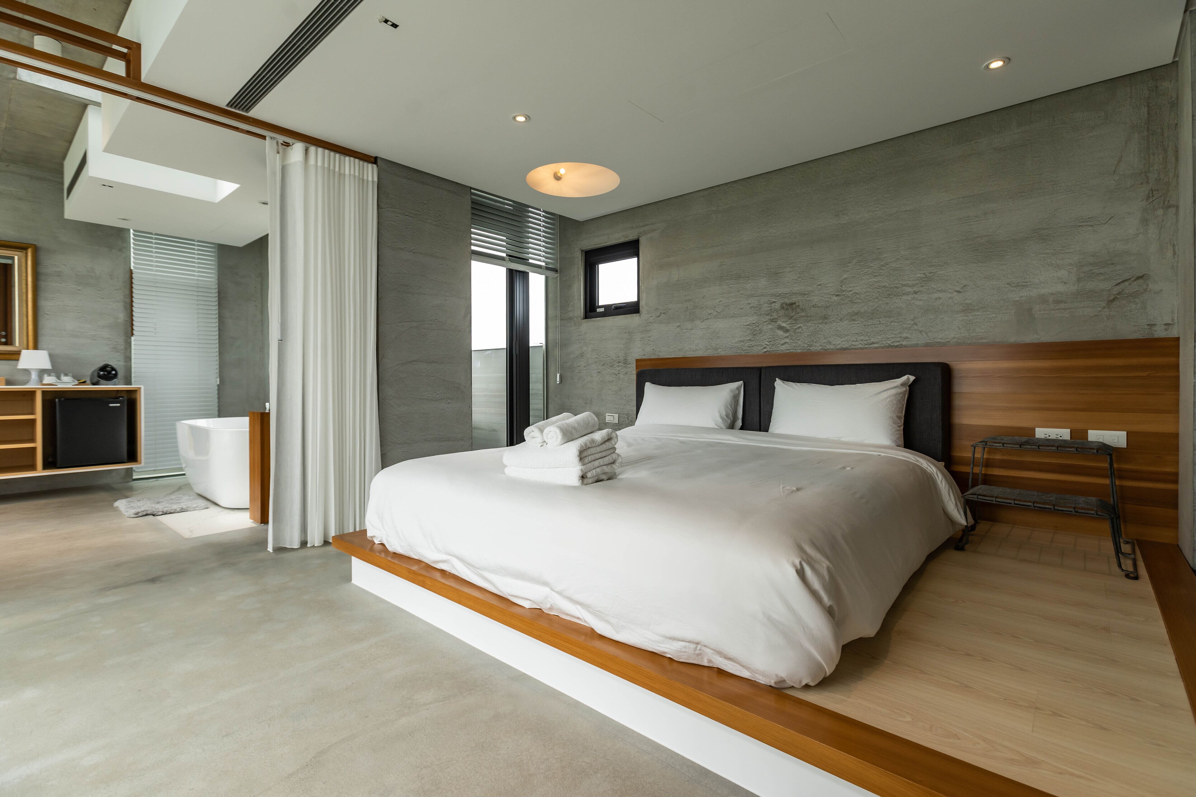 A modern bedroom with a large bed, a wooden headboard, and a built-in bench.