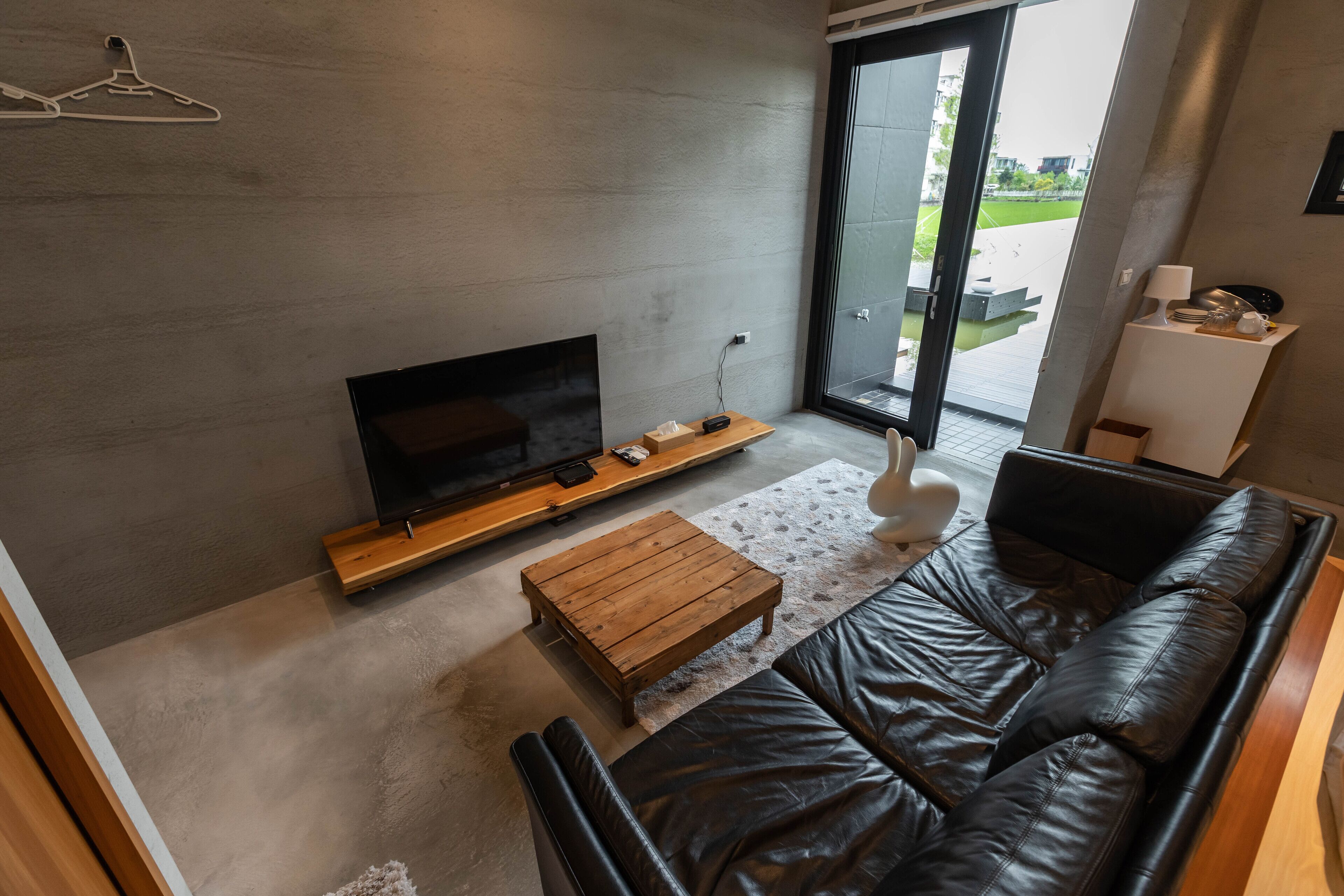 Uma sala de estar moderna com um sofá de couro, mesa de centro de madeira e uma TV de tela plana sobre um suporte de madeira.