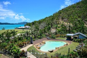 A resort with a swimming pool, lounge chairs, and a view of the ocean. - Frangipani Lodge 002, Beachfront Apartment on Hamilton Island (Hamilton Island)
