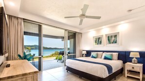 Une chambre d’hôtel moderne, dotée d’un grand lit, d’un bureau et offrant une vue sur la mer.