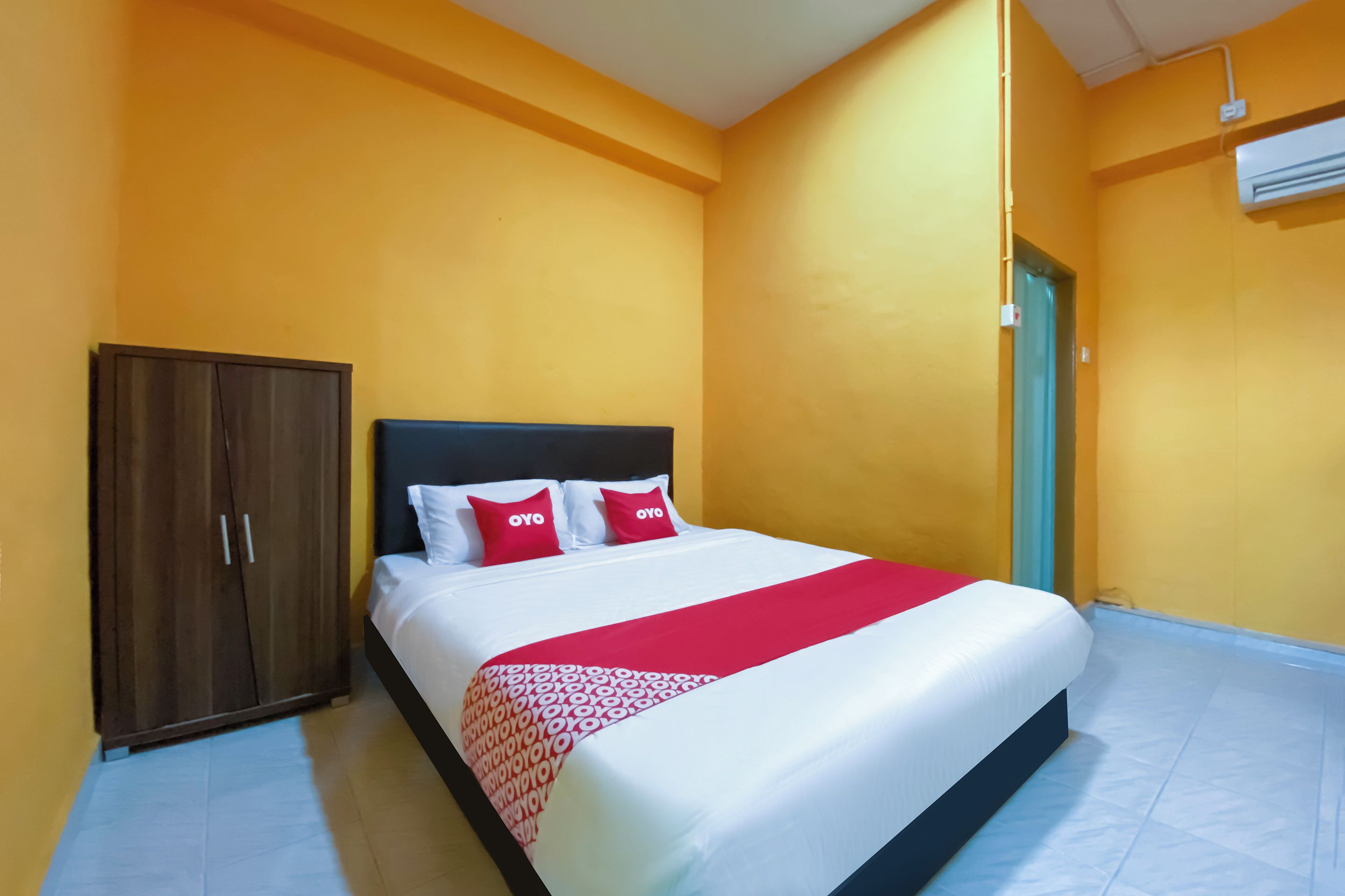 A hotel room with a bed, a wardrobe, and an air conditioning unit.
