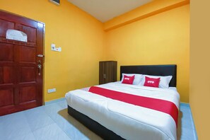 Une chambre d’hôtel avec un lit, une armoire et une porte.