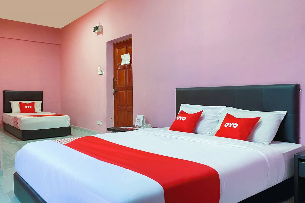 Een hotelkamer met twee bedden, elk met een rood-witte dekbedovertrek en bijpassende kussens.