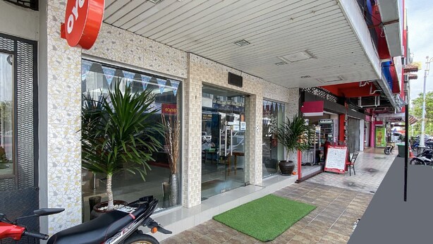 Ein Schaufenster mit rotem Schild, Glasfenstern und einer grünen Fußmatte davor.