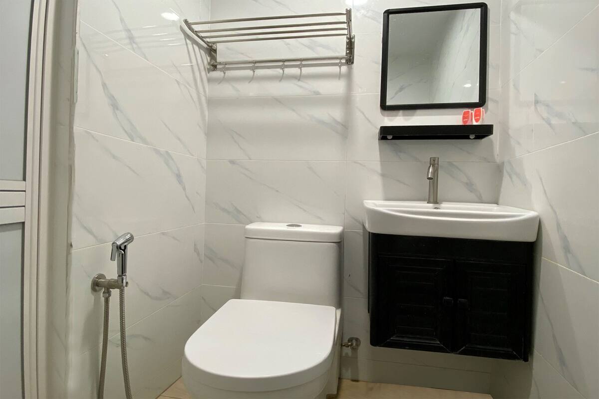 Een kleine badkamer met een wit toilet, een wastafel en een douche.
