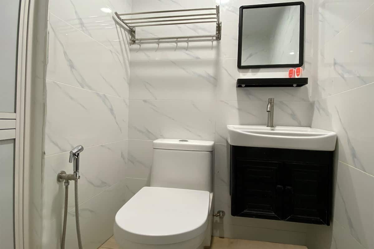 Casa de banho compacta com sanita branca, lavatório e chuveiro.