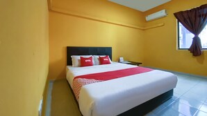 Ein Hotelzimmer mit einem großen Bett, einem Nachttisch, einer Klimaanlage und einem Fenster mit Vorhängen.