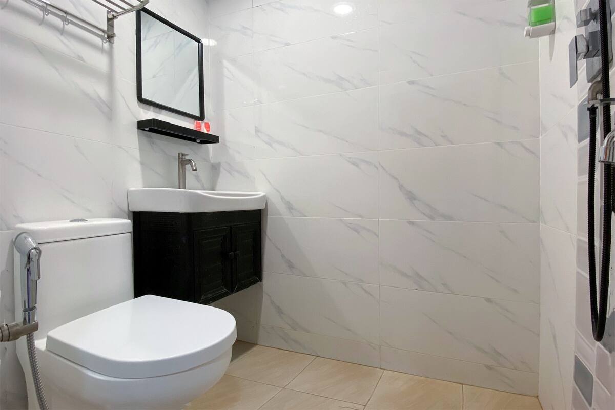 Een badkamer met toilet, wastafel en spiegel.