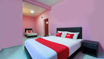 A hotel room with a large bed, a bedside table, and a door leading to another room.