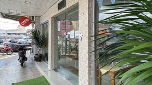 Ein Gebäudeeingang mit Glastür, Blumentopf und einem roten Schild.