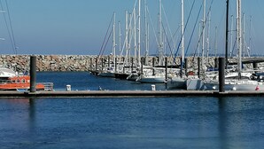 A marina with multiple sailboats docked, a stone wall in the background, and a clear blue sky. - Nice renovated apartment at the beach, thalasso (Roscoff)