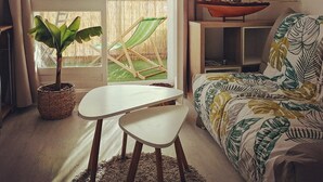 A cozy living room with a sofa, a small table, and a potted plant. - Nice renovated apartment at the beach, thalasso (Roscoff)