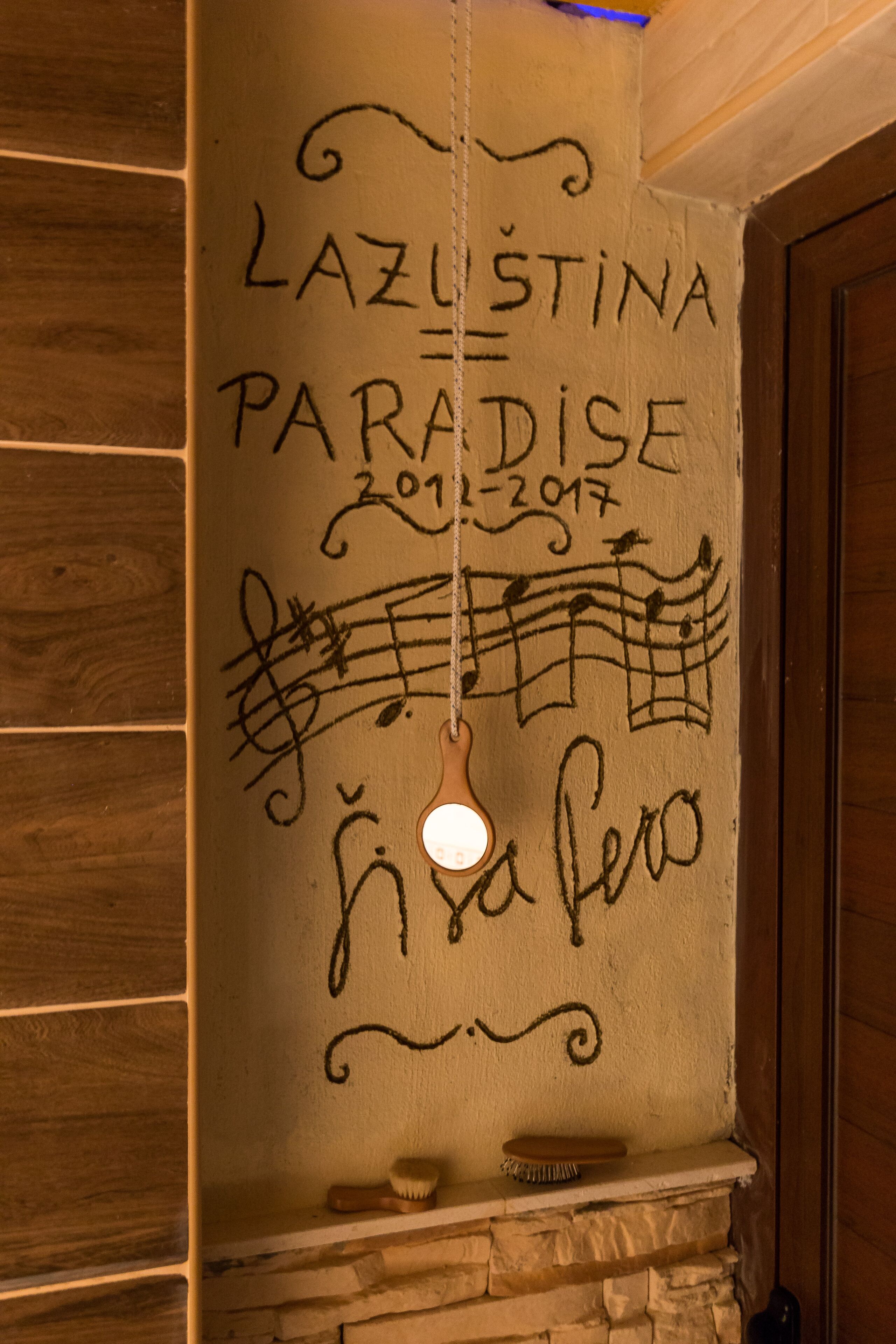 A wall with the text "LAZUSTINA PARADISE 2012-2017" and a hanging light fixture.